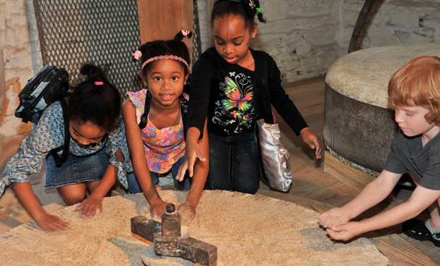 4 children look at the millstone at Peirce Mill