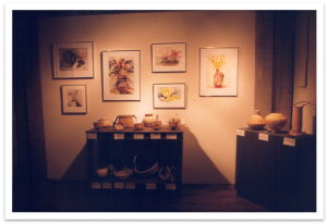 Paintings and pottery on display in a gallery.
