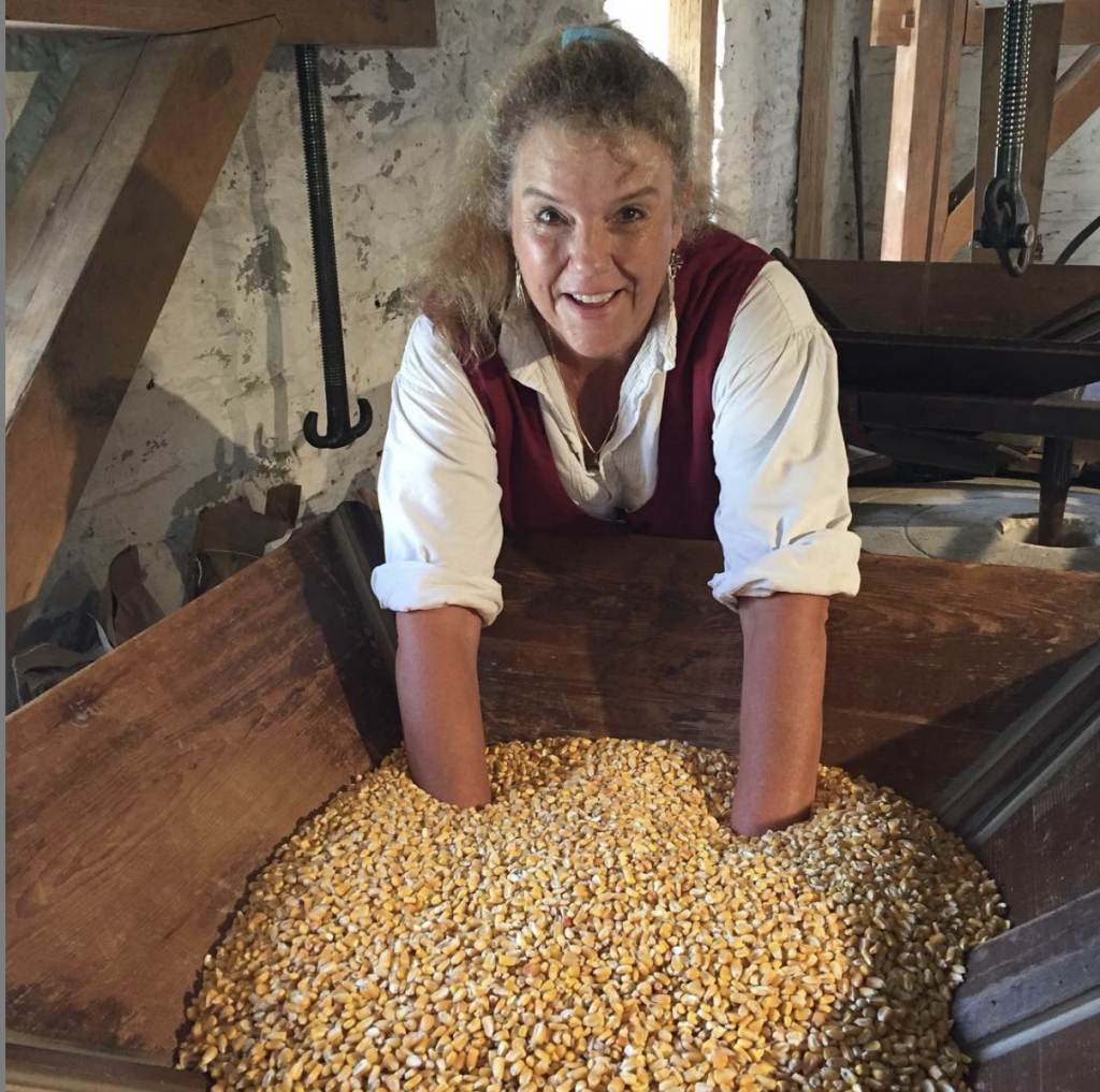 Photo of a miller with her hands in corn.