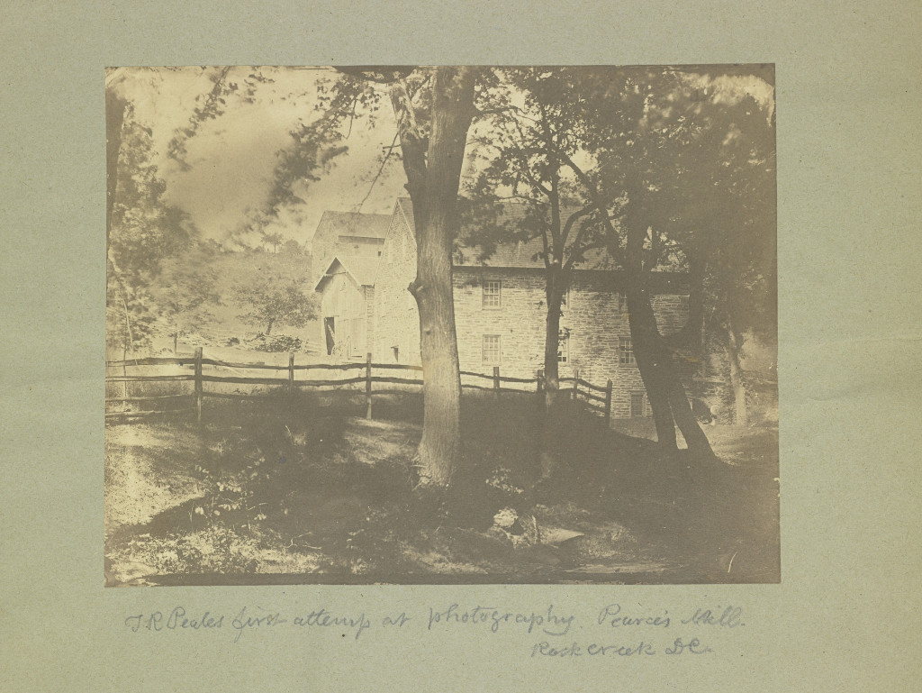 Very old black and white photograph of Peirce Mill with the barn in the distance. Handwritten caption