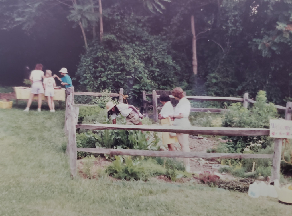People gather in a herb garden on a warm day in Rock Creek Park.