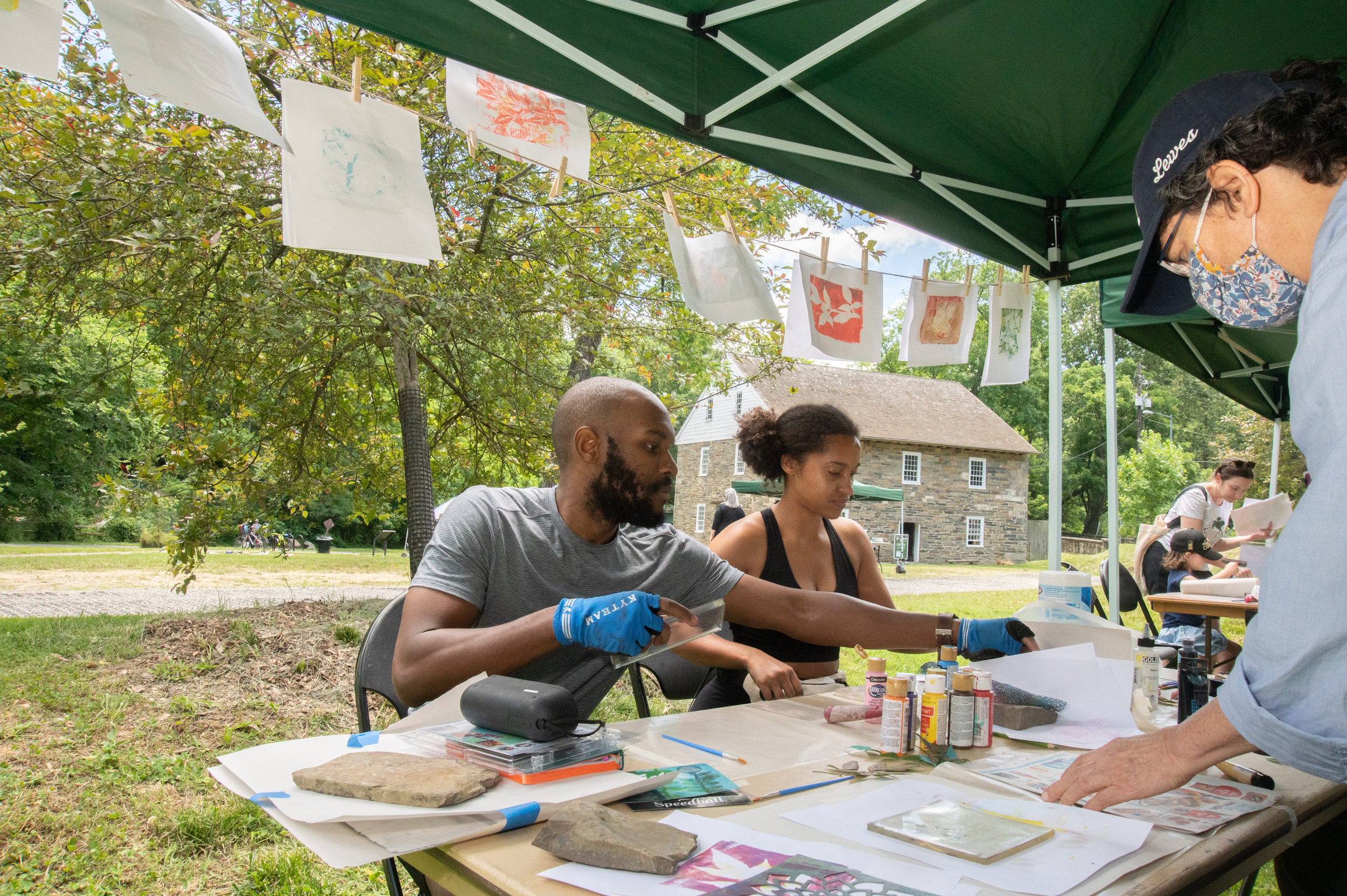 People making prints of leaves outside under a tent