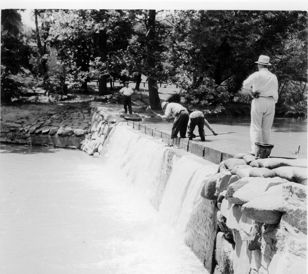 In an old black and white photograph workers raise a boulder dam.