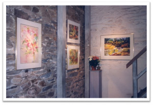 Paintings hang on a stone wall next to a staircase in an old building