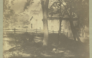 Very old sepia-toned photograph of Peirce Mill with two stone barns in distance.