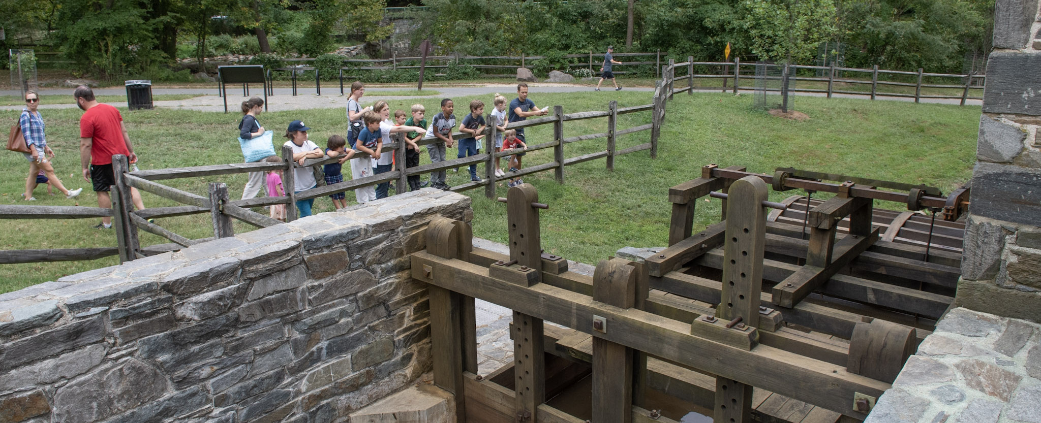 Watching wheels turn People stand on a fence watching a waterwheel