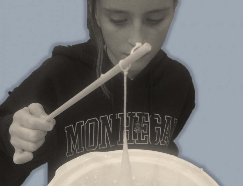 Girl makes a candle by dipping string into a crockpot full of wax