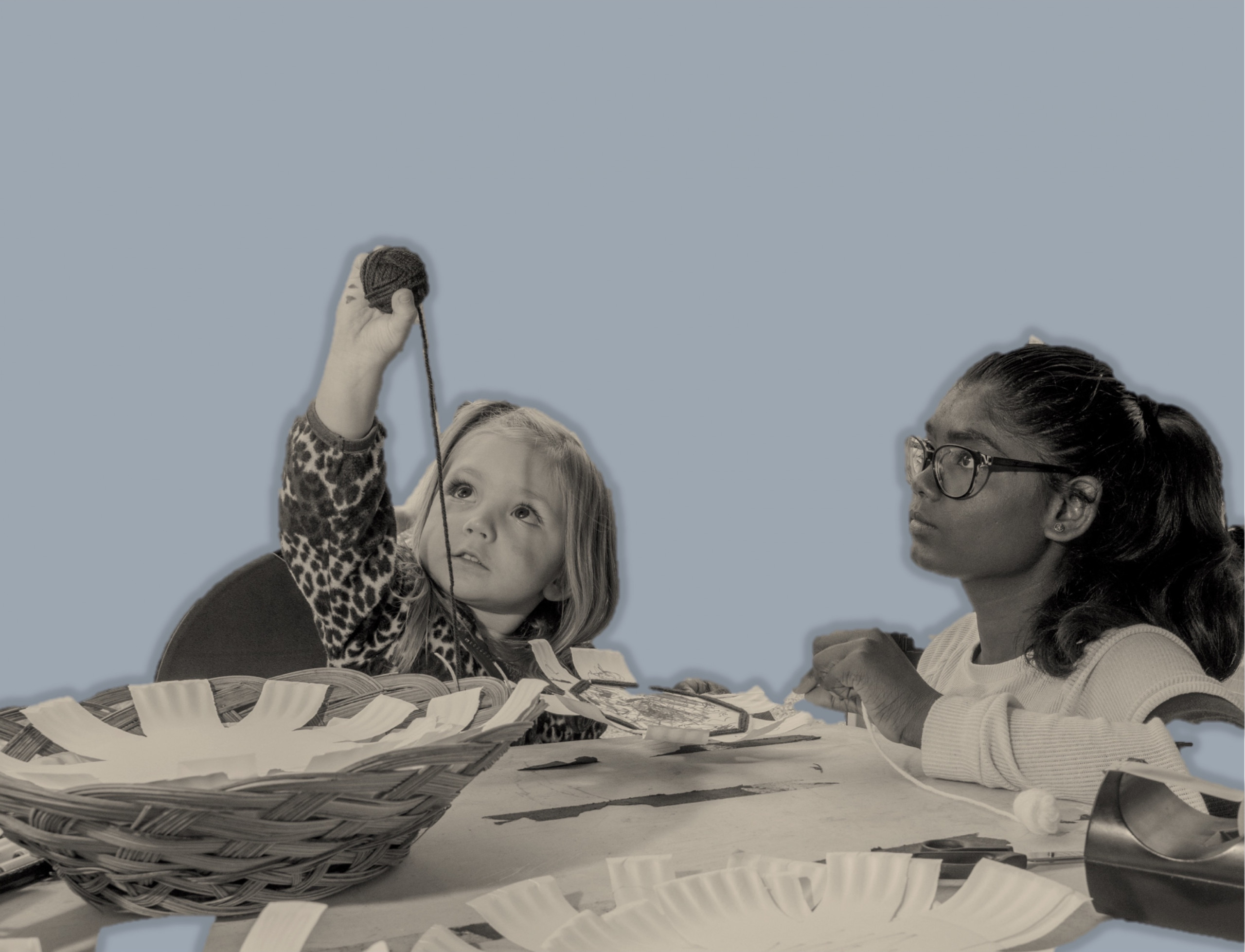 Two girls weave baskets using yarn and paper plates.