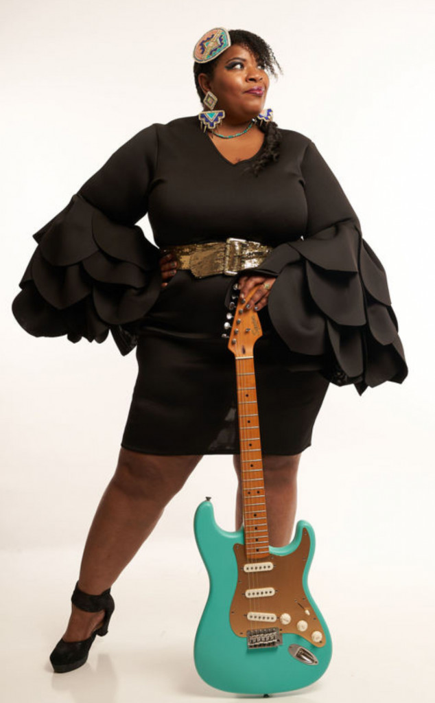 A woman standing holding a guitar