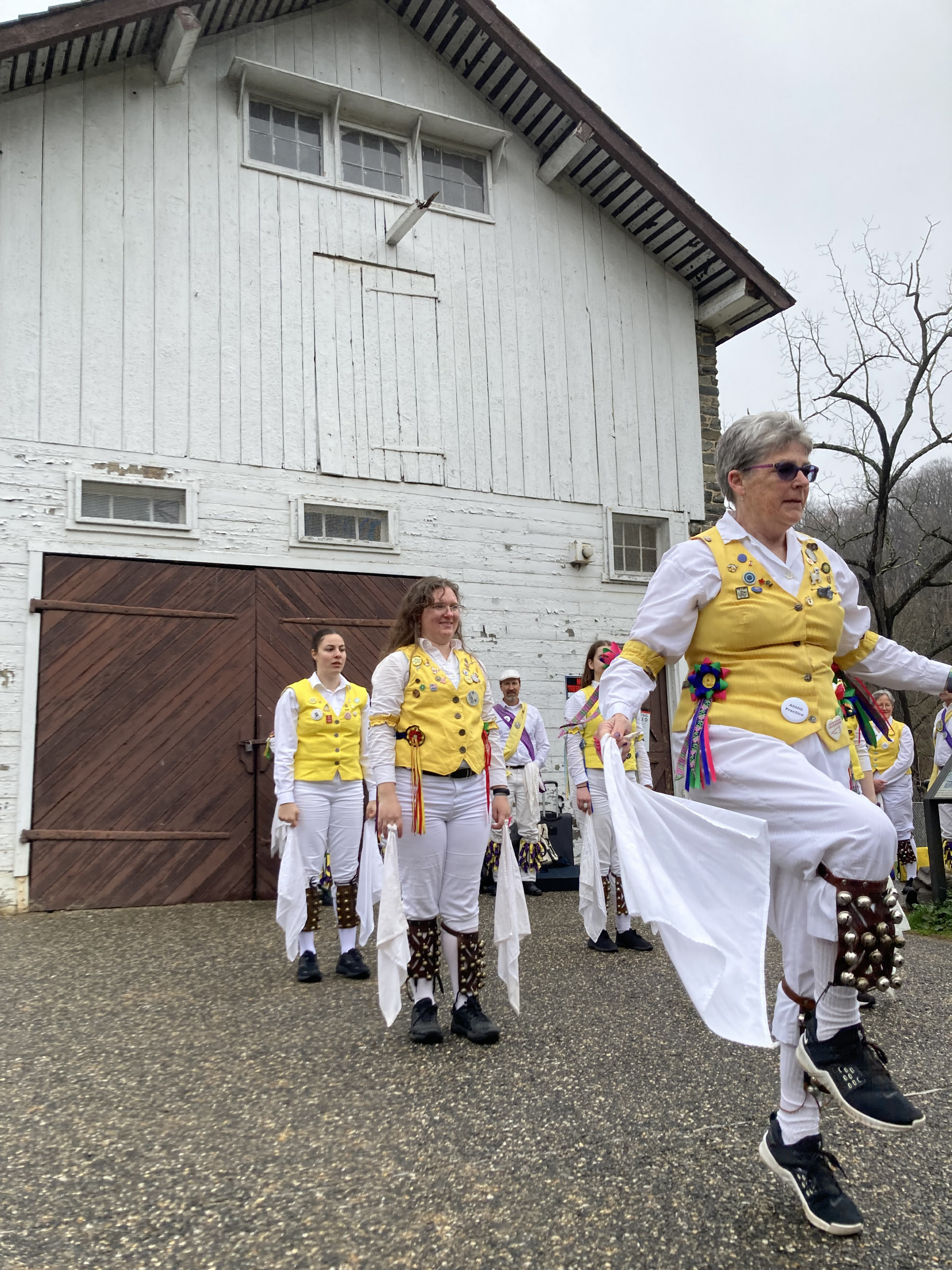 Women in yellow vests dance in front of Peirce Barn