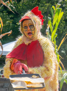 A performer in a chicken suit holds a tray with torillas