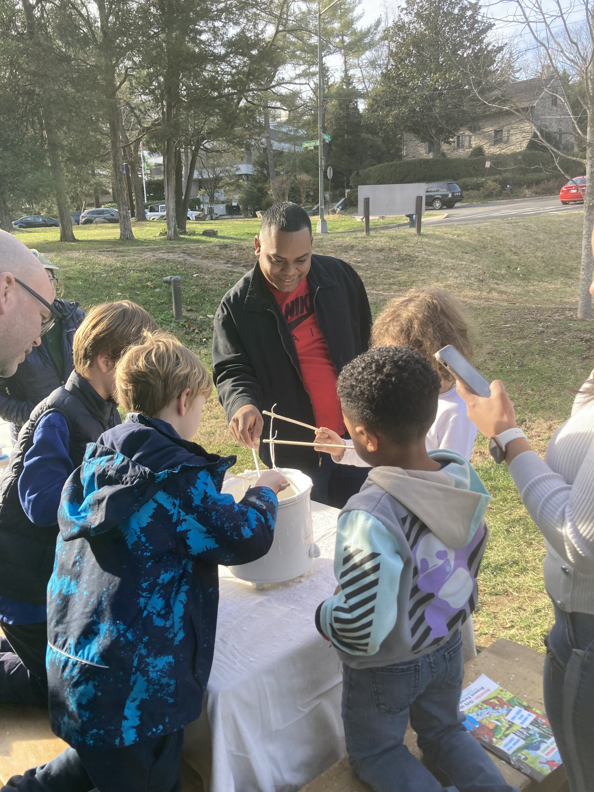 People stand around a crockpot making candles
