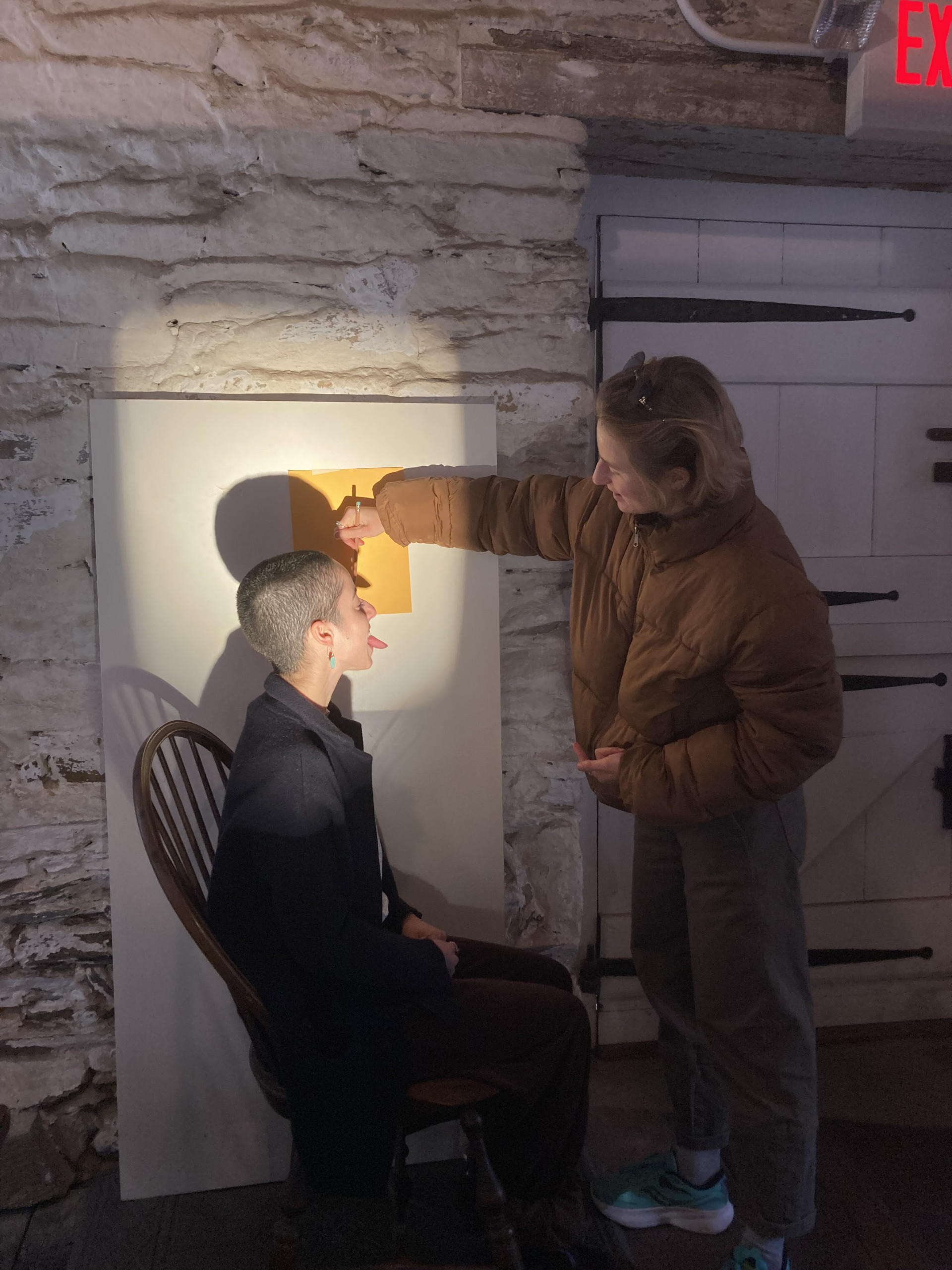 Two women make a silhouette portrait using a projector