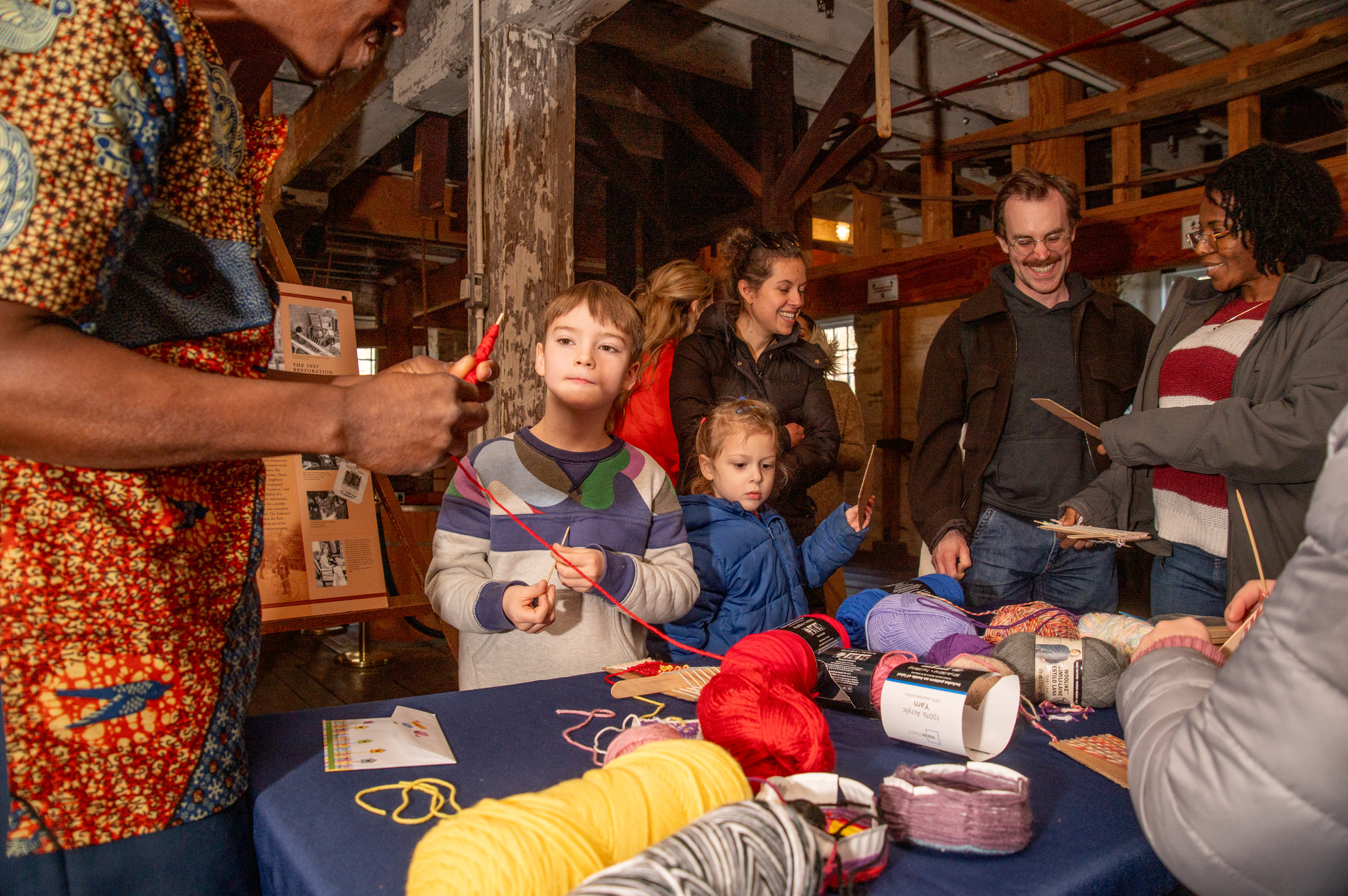People work together on yarn crafts inside an old building.