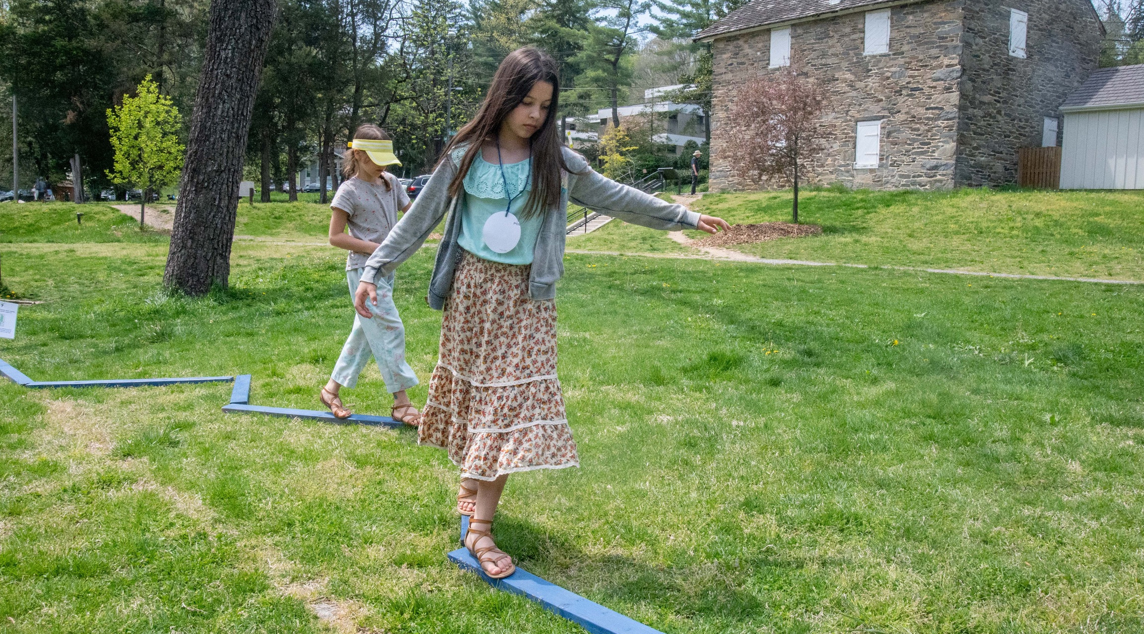 Two girls follow a wooden balance beam