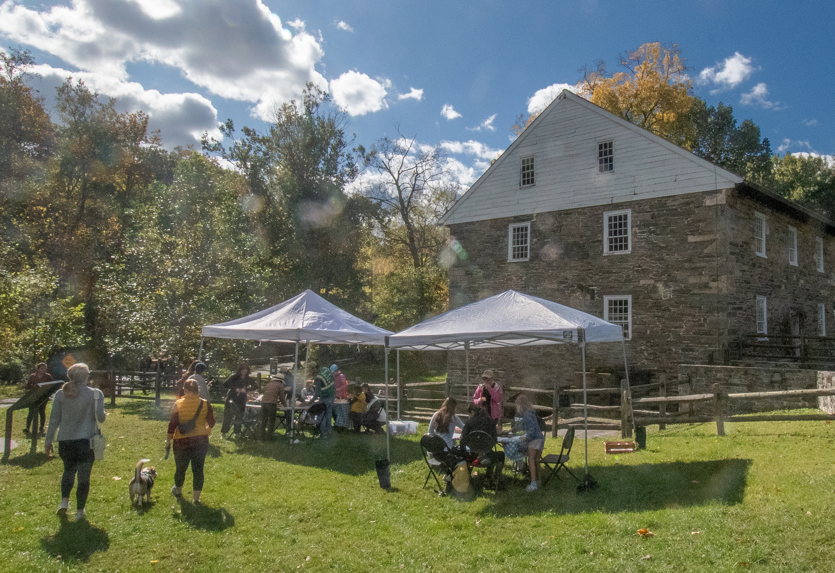 People walk toward tents sent up next to an old mill on a fall day