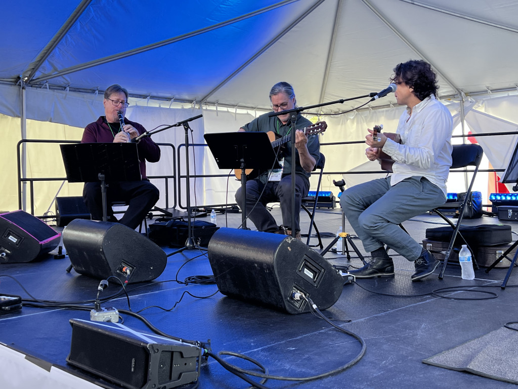 Three musicians playing instruments inside a tent
